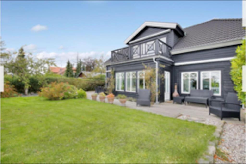 赫斯霍尔姆Eksklusivt hus på 250 m2 i naturskønne omgivelser的前面有草坪的黑房子