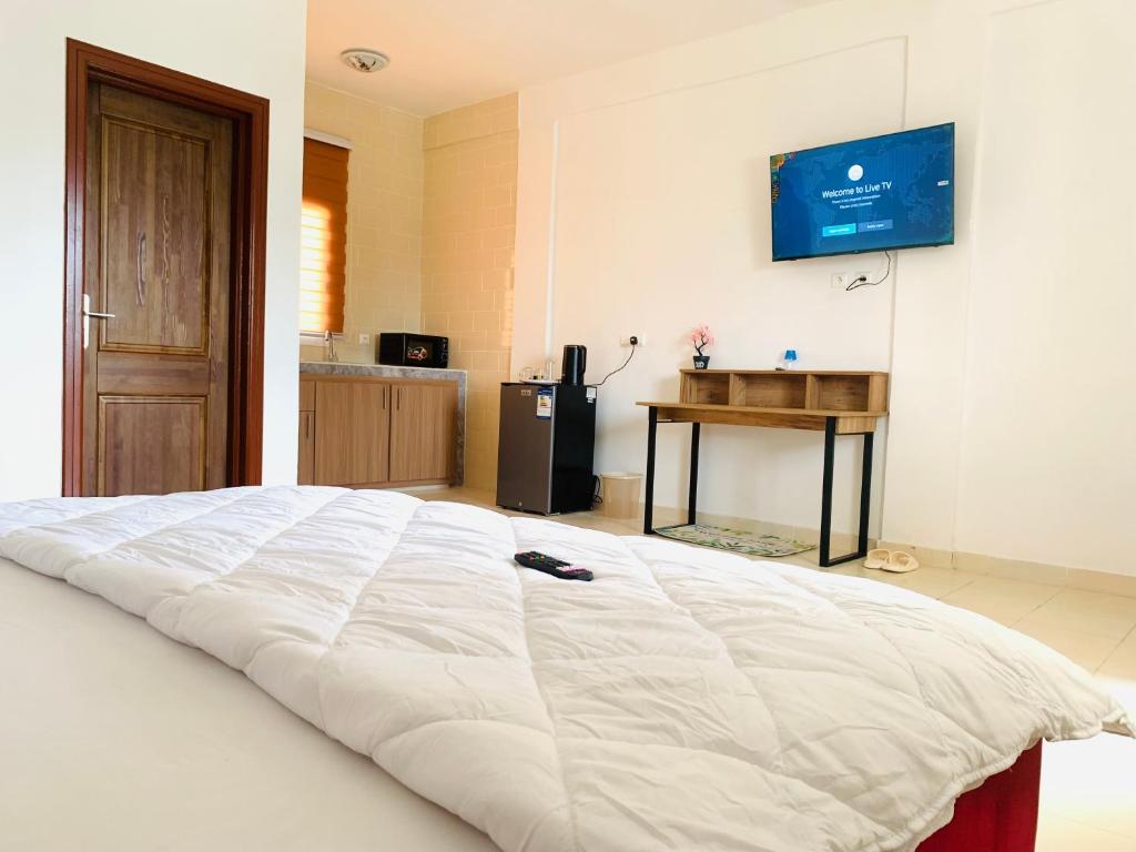 利伯维尔Namaste hotel & restaurant的卧室配有一张白色大床,墙上配有电视