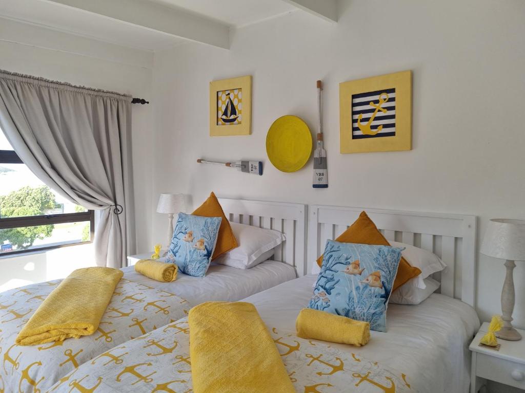 阿古拉斯South Of Africa的一间卧室配有两张带黄色和蓝色枕头的床