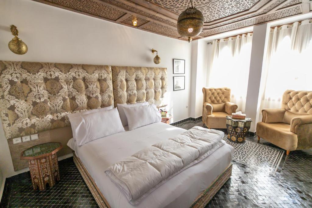 非斯Darif's Riad & Spa的一间卧室配有一张大床和两把椅子