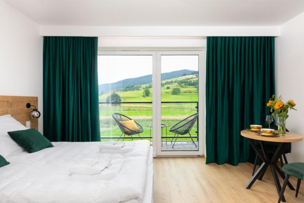 KoninaVilla Gorczański Zakątek的一间卧室配有一张带绿色窗帘的床和一个阳台