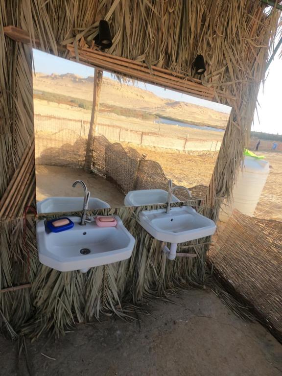 Dār as Salāmflamingo camp的一间位于稻草小屋内且带两个水槽的浴室