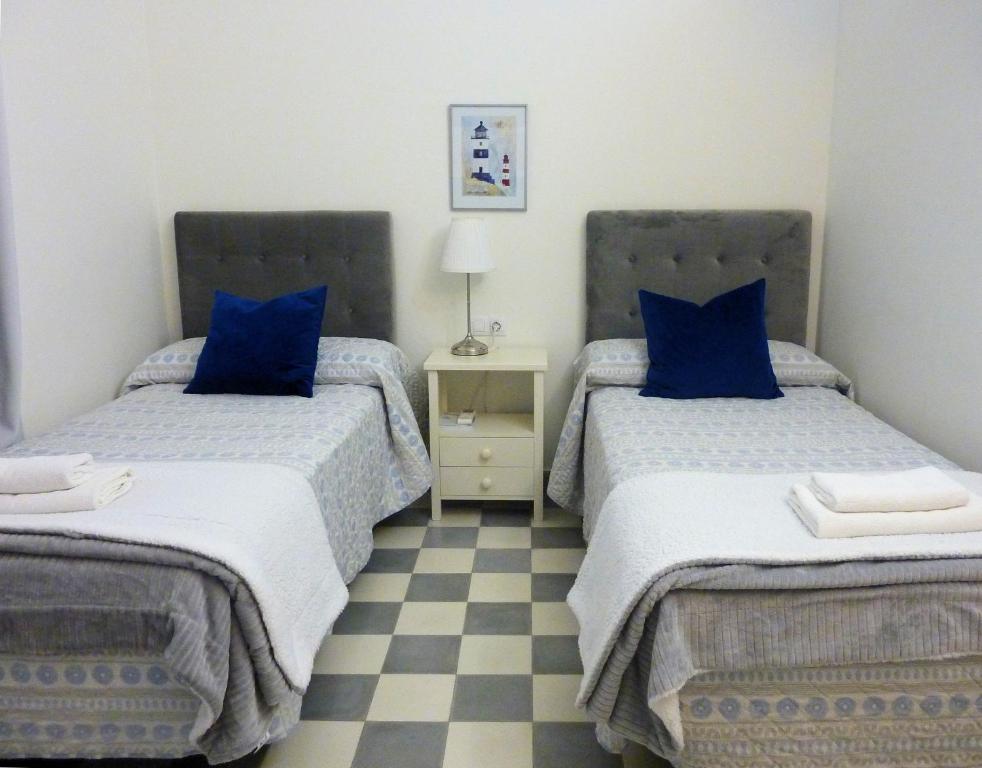 加的斯APARTAMENTO APODACA的一间卧室配有两张带蓝色枕头的床和 ⁇ 格地板