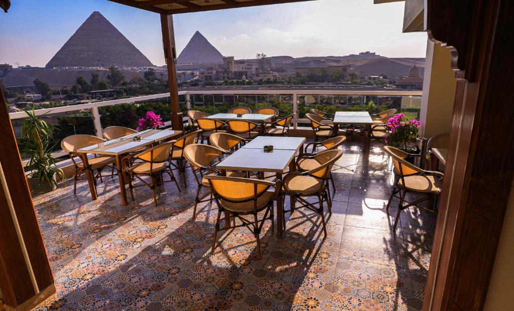 开罗DouDou Pyramids View Hotel的一个带桌椅和金字塔的庭院