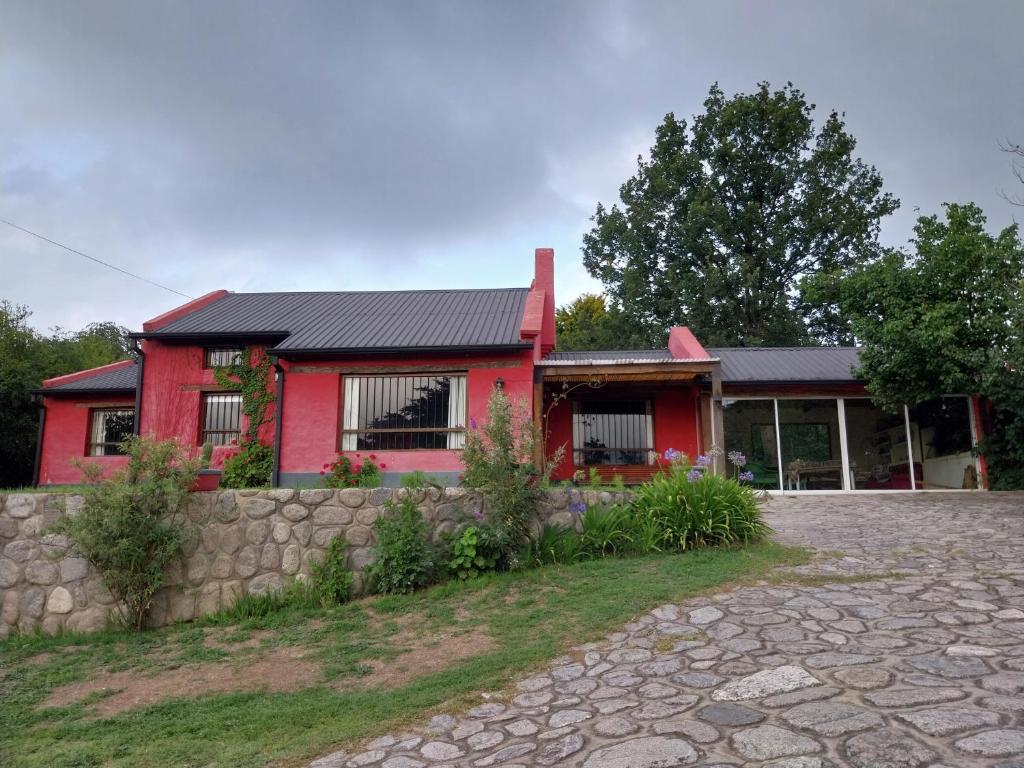 圣米格尔·德·图库玛Casa de campo en tafi del valle的前面有石头车道的红色房子