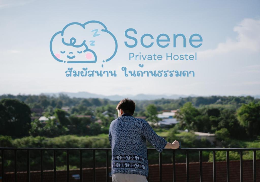 南府Scene Private hostel的站在围栏上看着一个读书宁静私人酒店的标志的女人