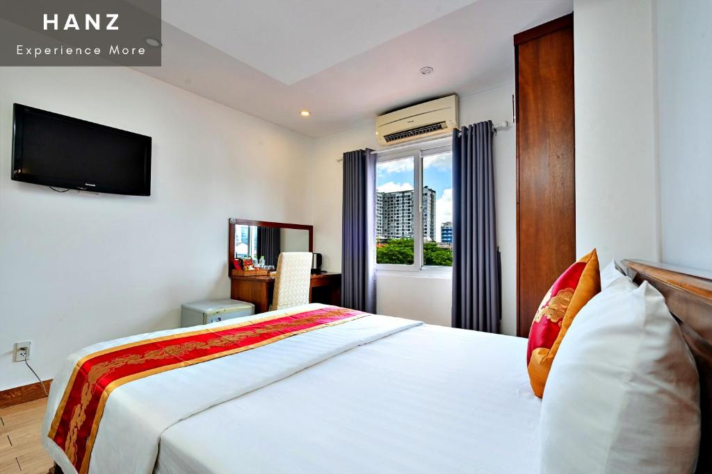 胡志明市HANZ King Airport Hotel的一间卧室设有一张带电视和窗户的床。