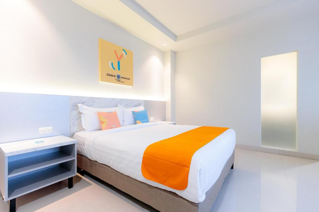 泗水Sans Hotel 88 Andalan Surabaya by RedDoorz的一间卧室配有一张带橙色和白色毯子的床