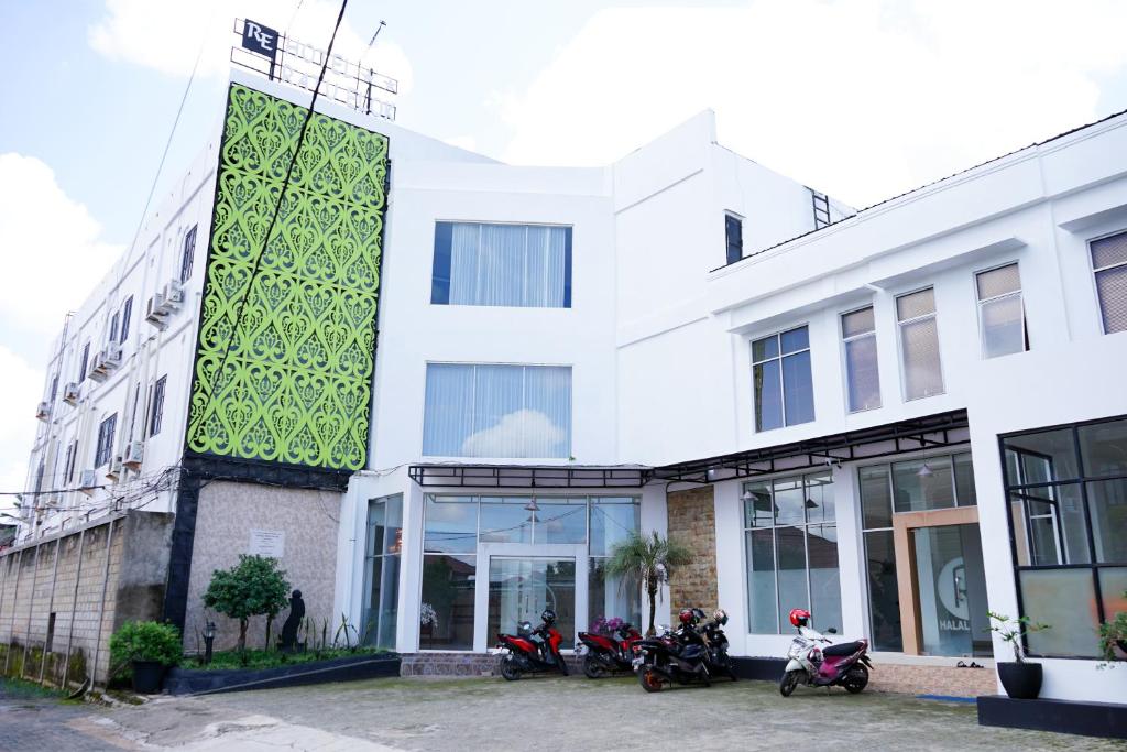 MartapuraUrbanview Hotel Ratu Elok Syariah Banjarbaru by RedDoorz的一座白色的建筑,前面停有摩托车
