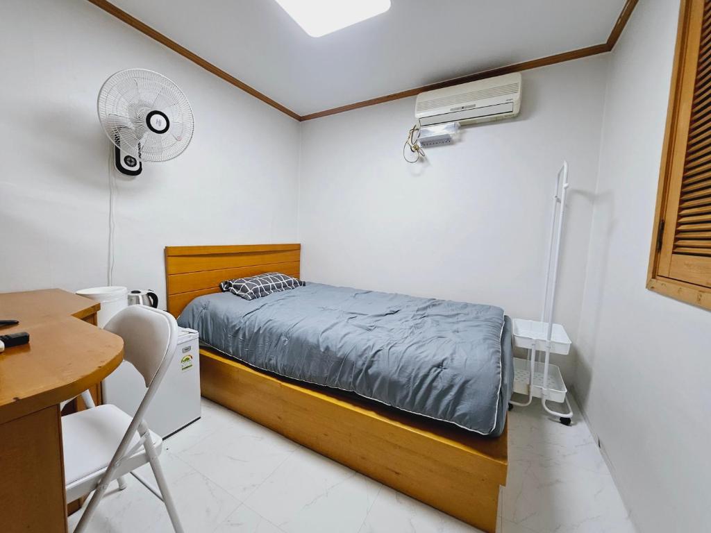首尔K Highstel的一间卧室配有一张床和一张带风扇的书桌