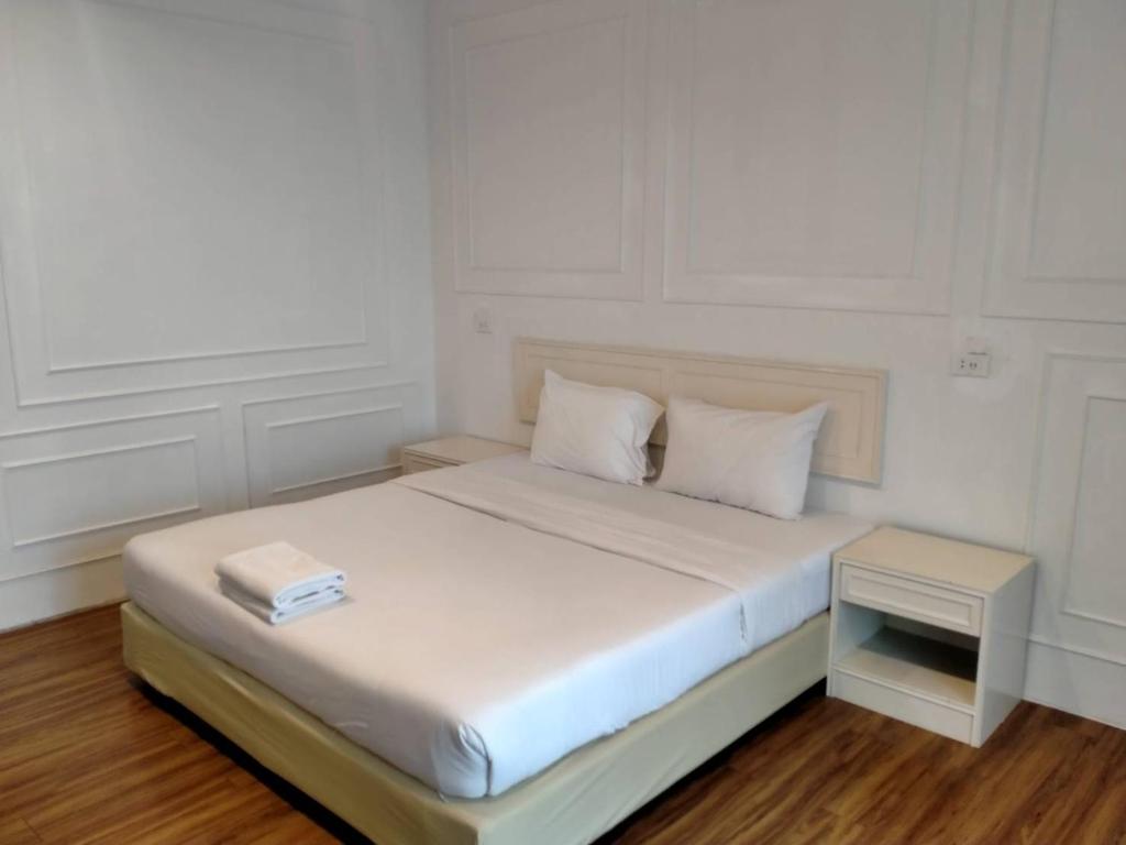 信武里府金龙度假酒店的一间白色卧室,配有一张带书籍的床