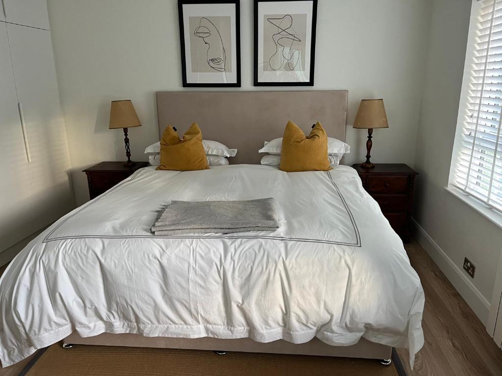 恩尼斯科西Central town location apartment的一张白色的床,上面有两个黄色的枕头
