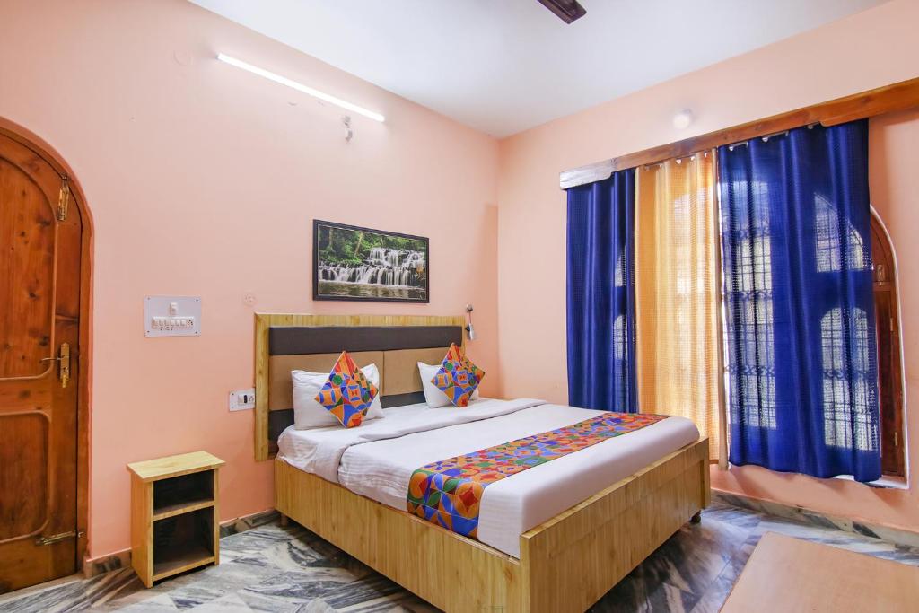 库尔卢FabExpress Malti Guest House的一间卧室配有一张带蓝色窗帘的大床