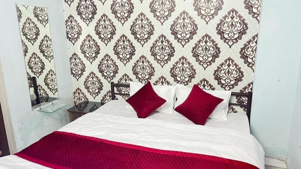 拉特纳吉里Hotel Vrindavan Ratnagiri的卧室内的白色床和红色枕头