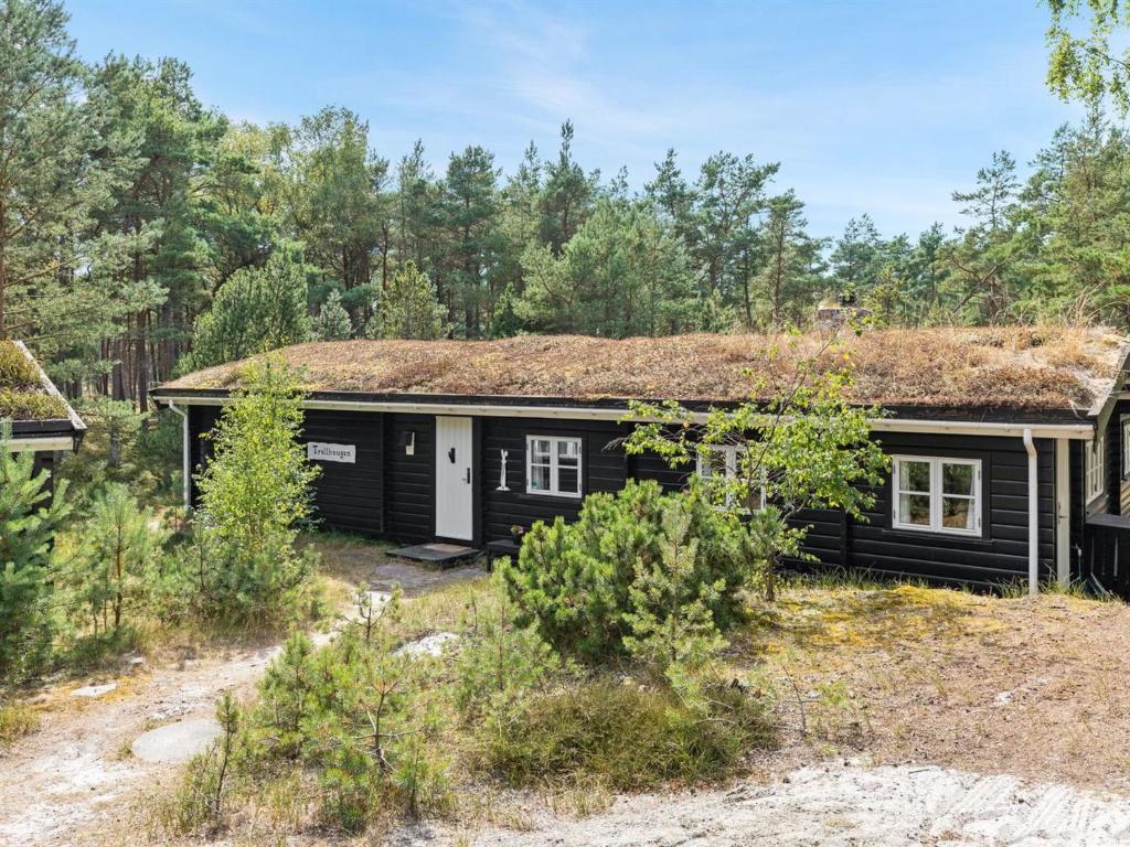 维斯特索马肯Holiday Home Solfred - 200m from the sea in Bornholm by Interhome的一间设有草屋顶的黑色小房子