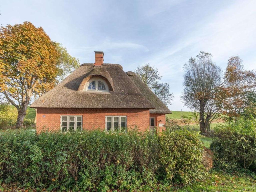 TetenbüllHoliday Home Deichwärterkate by Interhome的一座带茅草屋顶的老砖屋