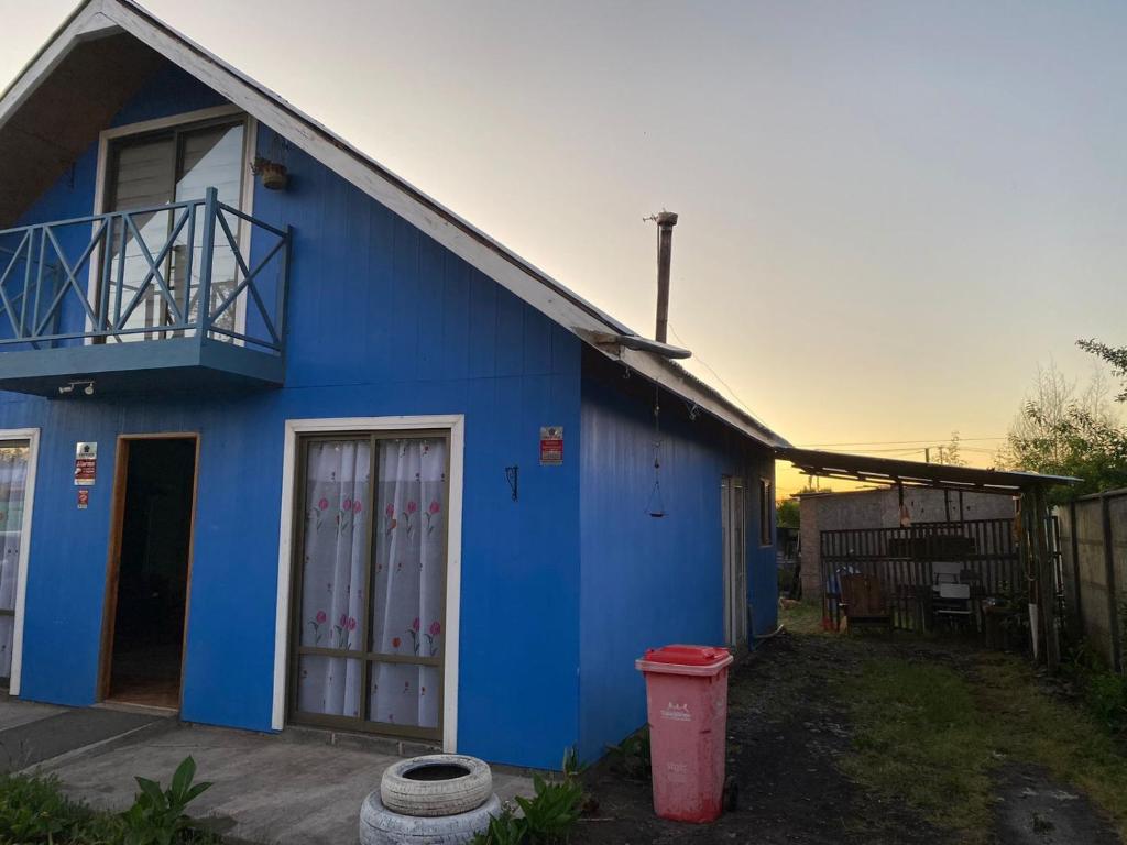 Guangualícasa familiar的前面有红垃圾桶的蓝色房子