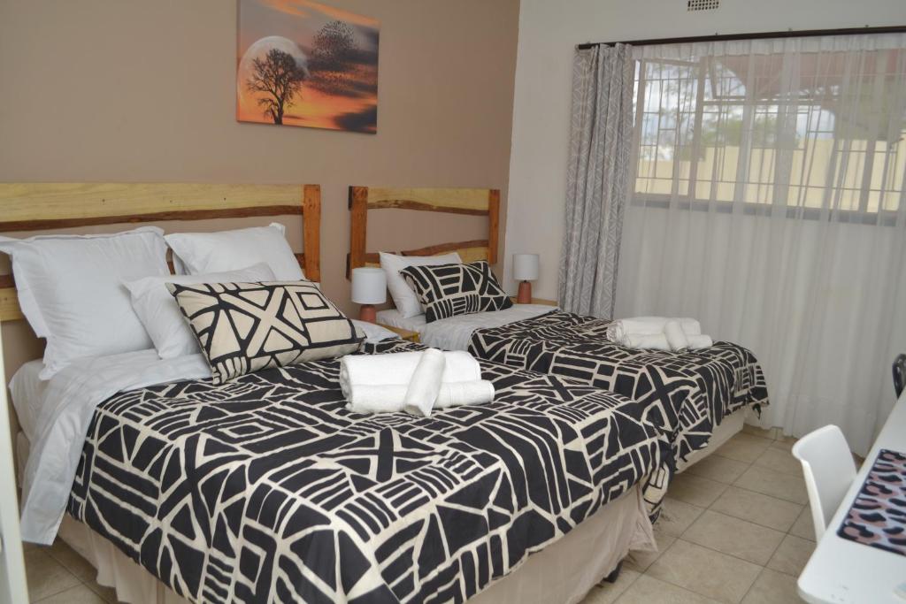 温特和克Wanjara's Nest的卧室内的两张床,配有黑白色的被子