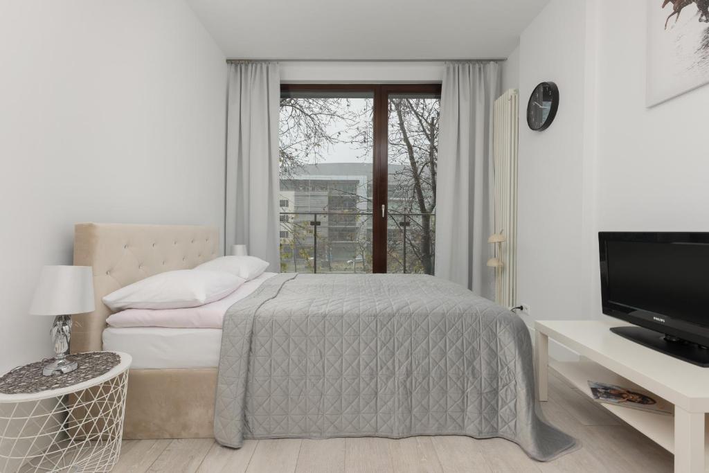 华沙Elegant White Studio with Balcony in Warsaw by Renters的白色的卧室设有床和窗户