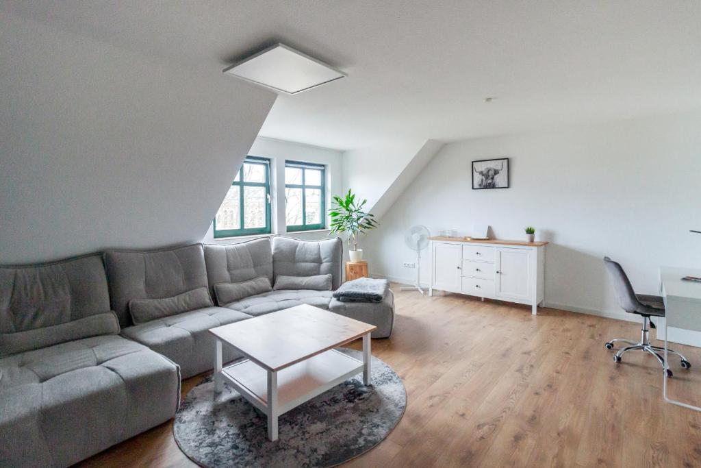 马格德堡Ferienwohnung "Kapellmeister" mit Klimaanlage in allen 4 Schlafbereichen, großes Wohnzimmer mit Smart TV und Big Sofa的客厅配有沙发和桌子