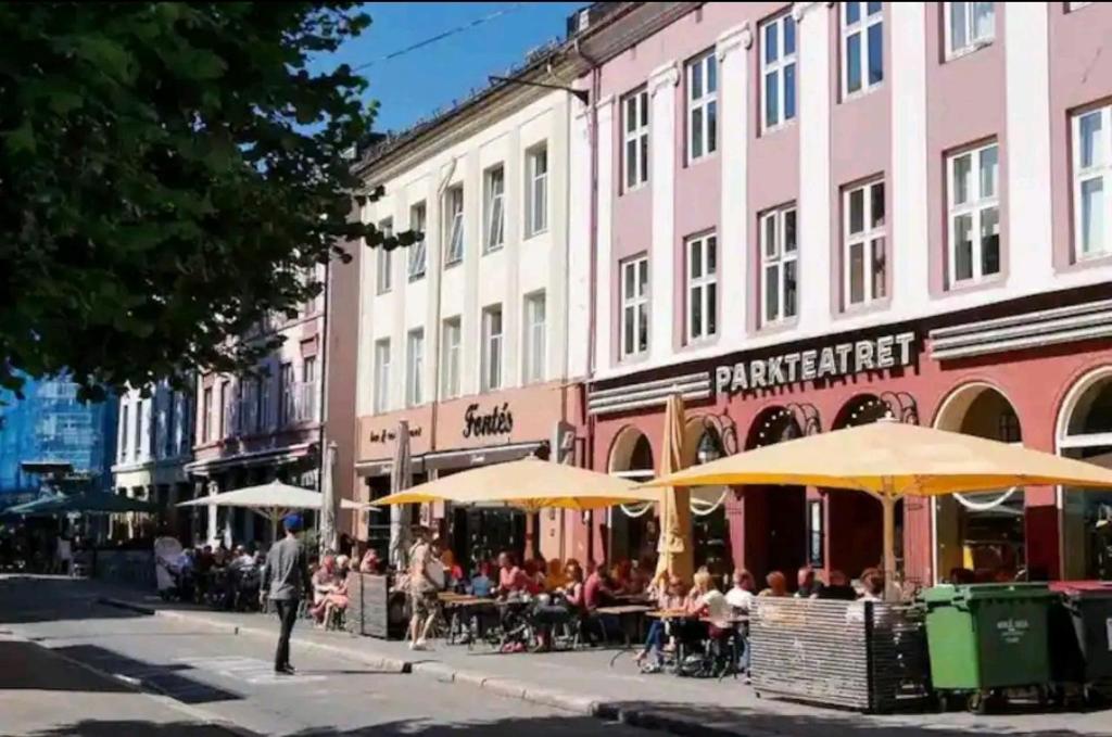 奥斯陆Central Grünerløkka, close to city center的一群人坐在街上的桌子下,在雨伞下