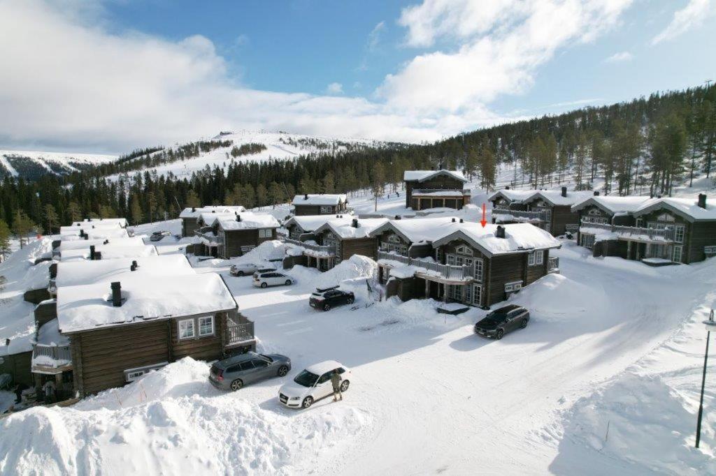 萨伦Exklusiv ski in-ski out stuga, i Hundfjället Sälen的雪覆盖的村庄,有汽车停在雪中