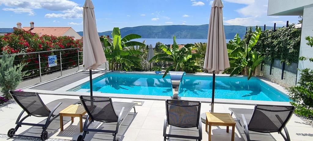 皮内兹齐Luxury villas White Sails的庭院内一个带椅子和遮阳伞的游泳池