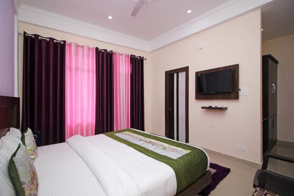 达兰萨拉OYO Hotel Chandni的卧室配有一张床,墙上配有电视。