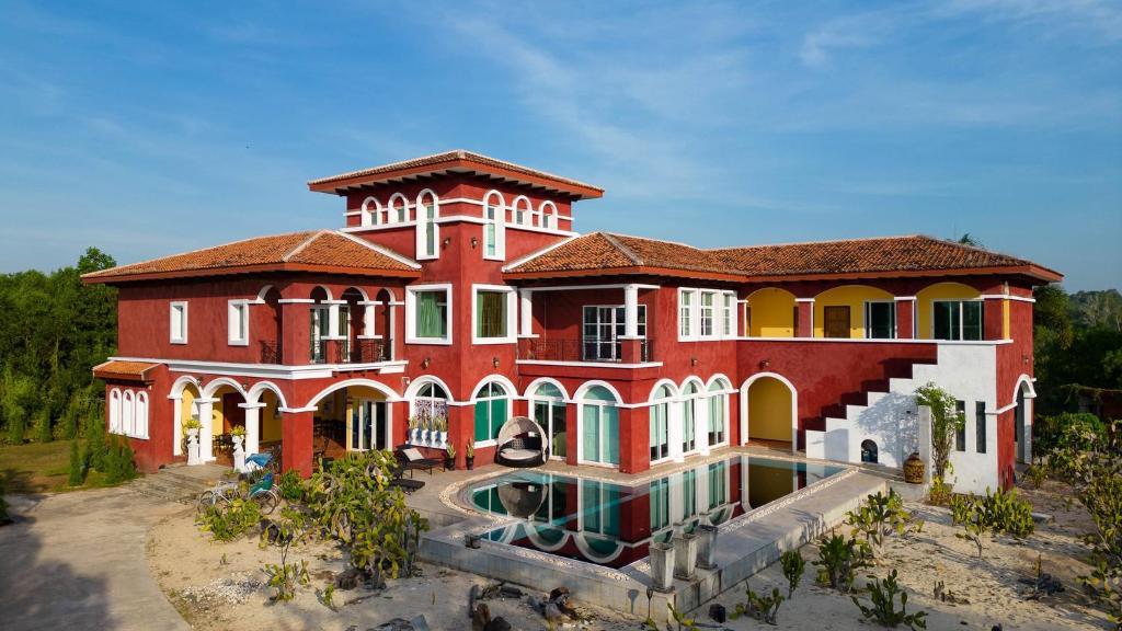 梅尔皮姆Hacienda Resort - Mae Phim的一座红色的大房子,前面设有一个游泳池