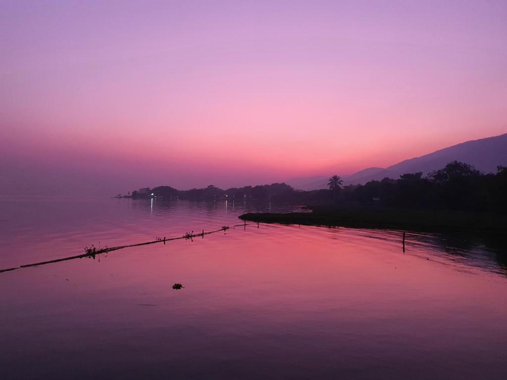 El EstorHotel Ecológico Cabañas del Lago的粉红色和紫色的日落在水体上