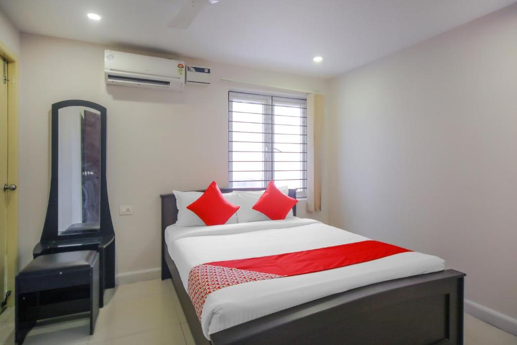 钦奈Pride Hospitality Nungambakkam的一间卧室配有一张带红色枕头的床和电视。