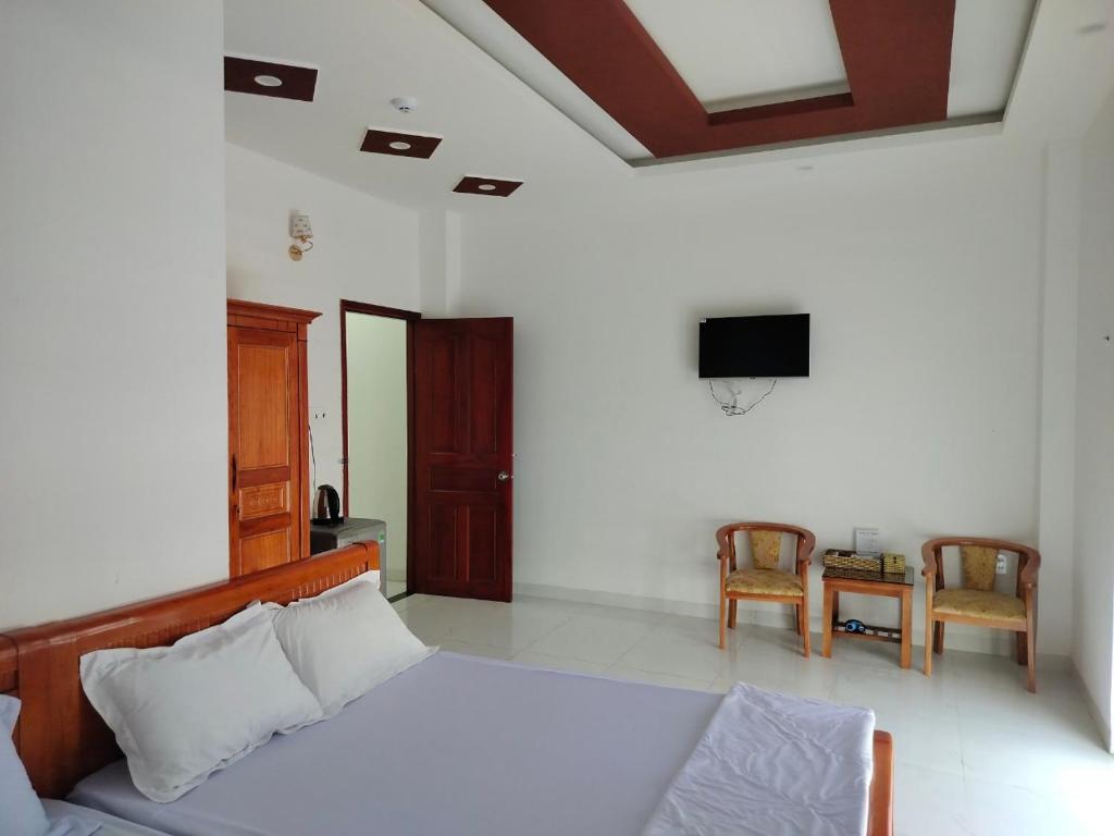 Ấp Cái GiáKhách sạn Gia Nghiêm 2的一间卧室配有一张床、一台电视和一张桌子