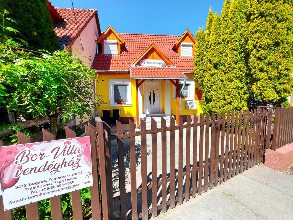 博加奇Bor-Villa vendégház的黄色房子,带有木栅栏和标志