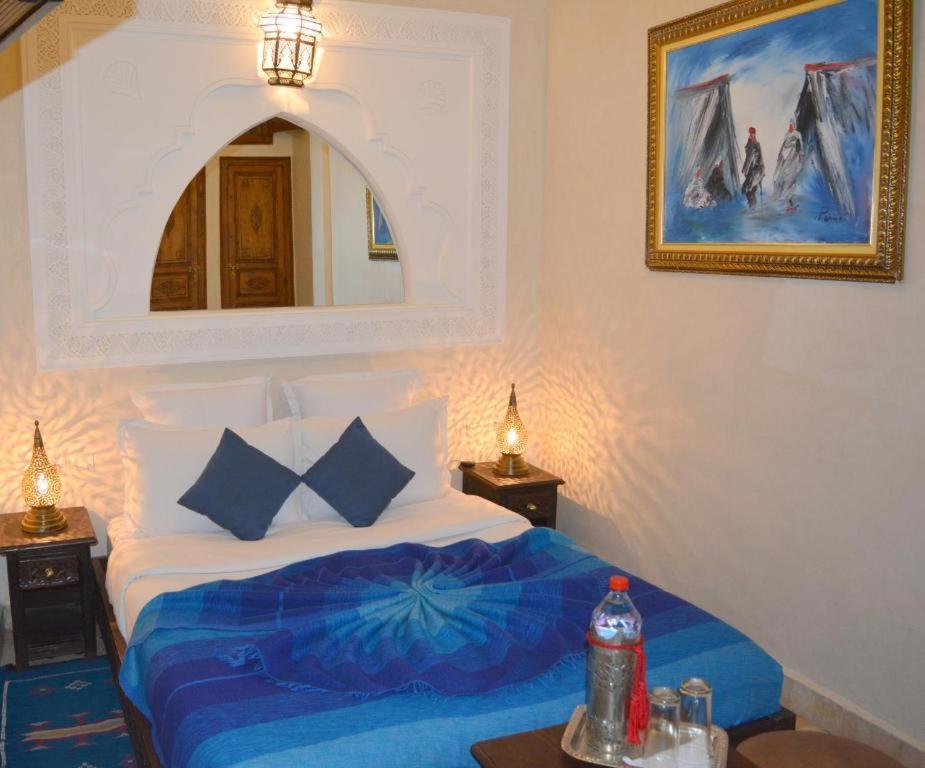 马拉喀什Riad Ghali Hotel & SPA的一间卧室配有一张带蓝色床单和镜子的床