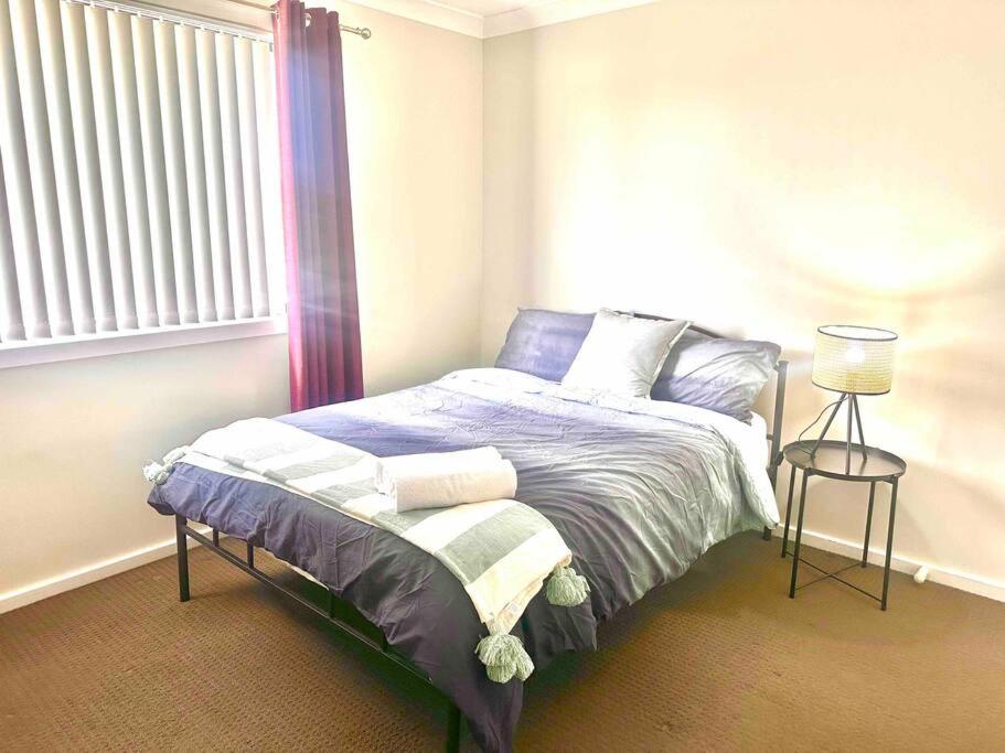 杰斯蒙Maya Newcasle 6 bedrooms home的一间卧室配有一张带紫色床单的床和窗户。