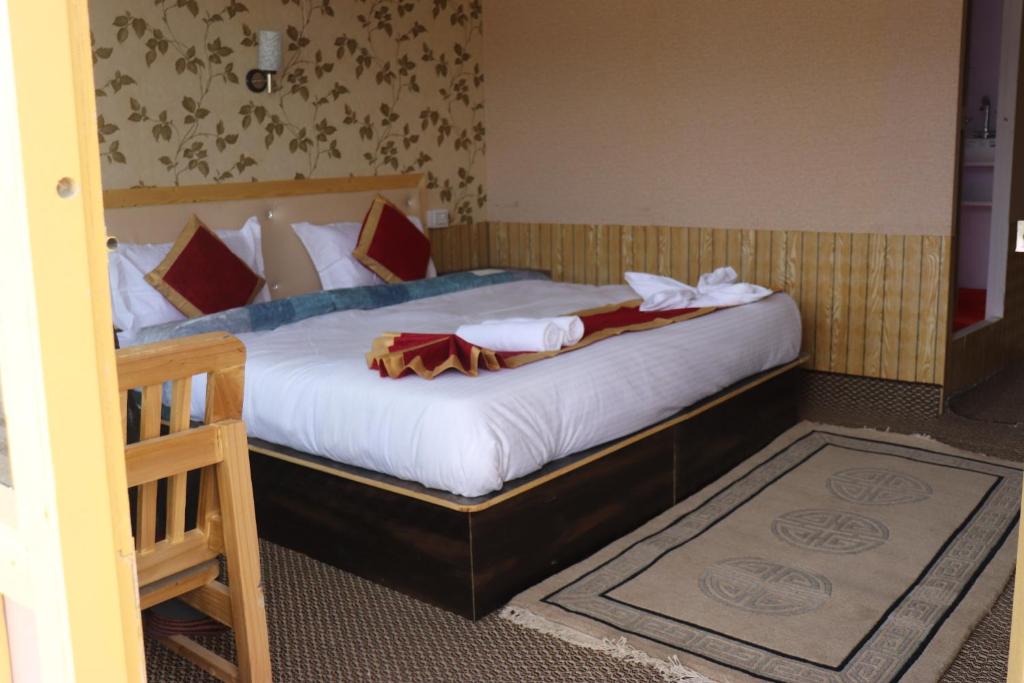 MerukThe hidden heaven cottage pangong merak的一间卧室配有带白色床单和红色枕头的床。