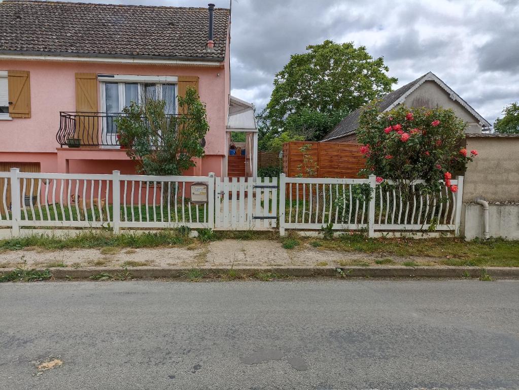 Saint-LoupMaison de village的粉红色房子前面的白色围栏