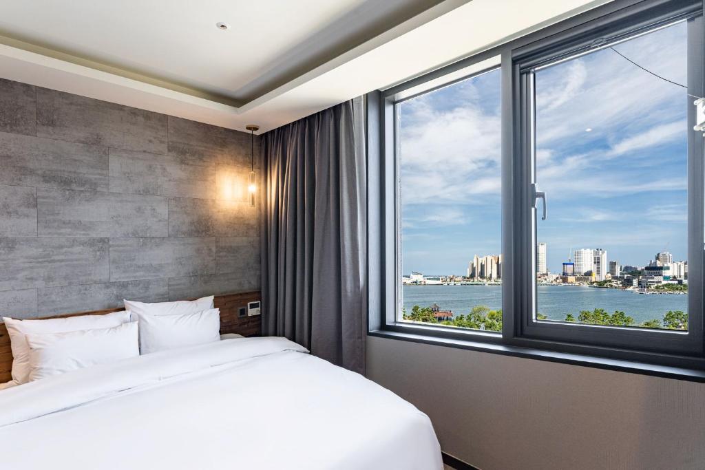 束草市Sokcho Business Hotel CAMEL的一间卧室设有一张床和一个大窗户