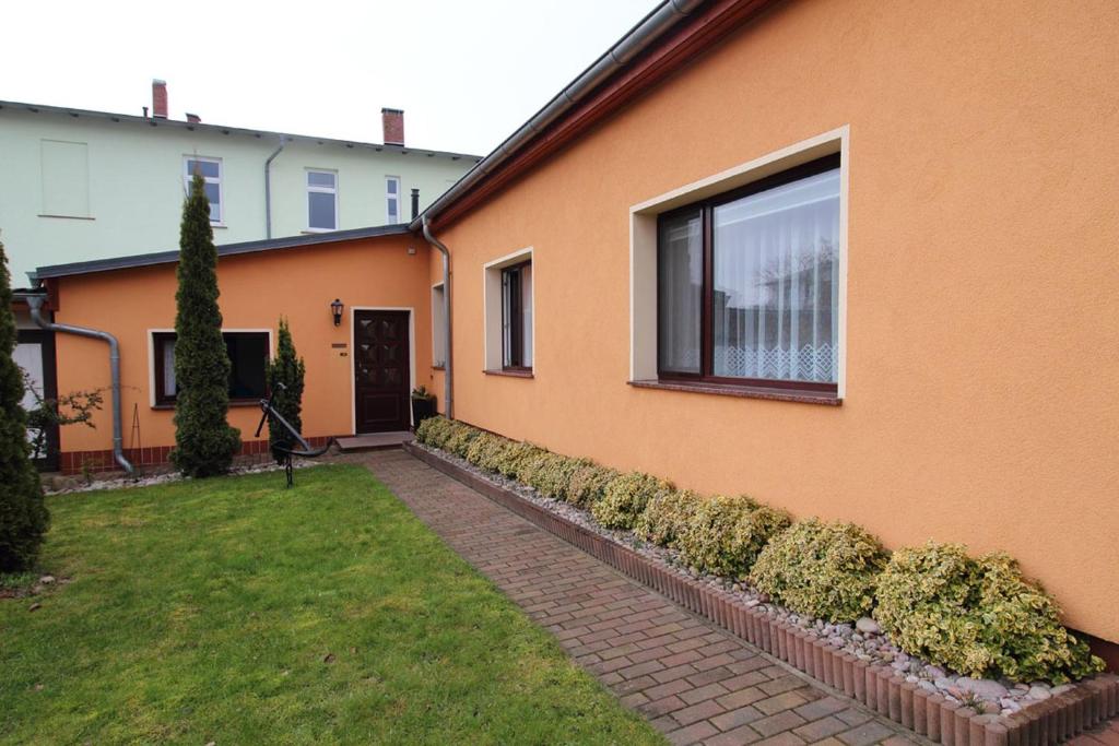 萨斯尼茨Ferienwohnung Kollwitz的橙色的房子,有窗户和院子