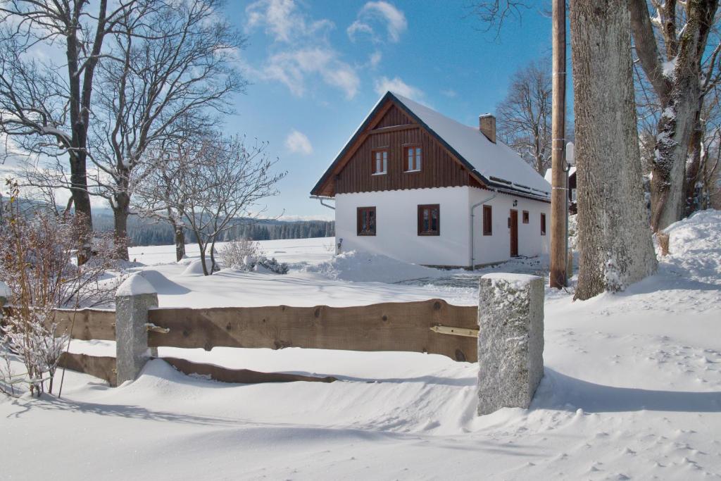 雷吉维兹Chalupa Rejvíz的雪中带木栅栏的房子