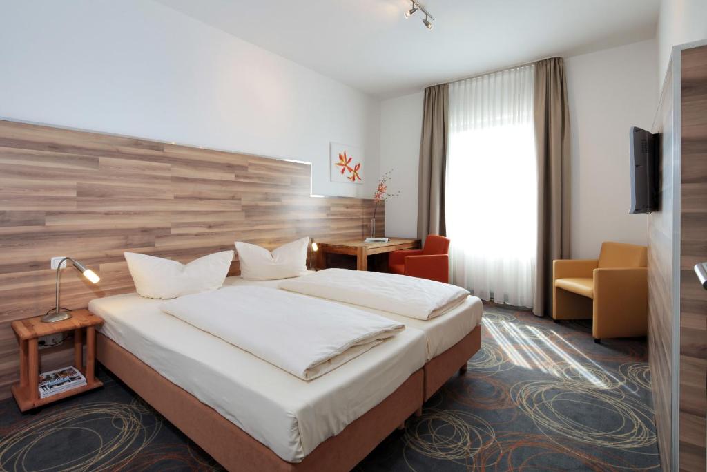 埃森佩杜尔公寓式酒店的酒店客房带一张大床和一把椅子
