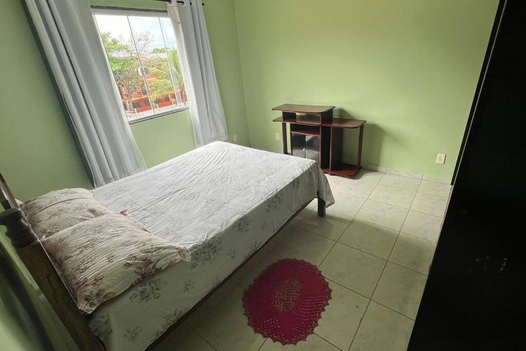 瓜拉派瑞Apartamento em Setiba的一间卧室设有一张床、一个窗口和一张桌子
