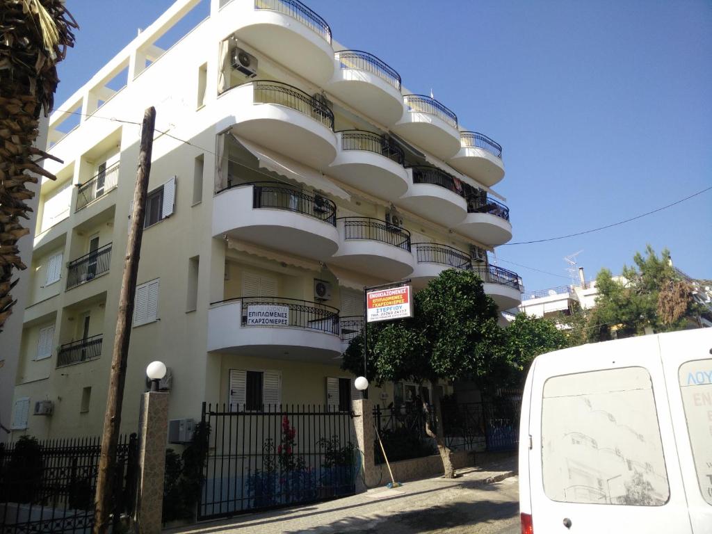 卢特拉艾季普苏Stergiou Edipsos的带阳台的白色建筑和停在前面的一辆面包车
