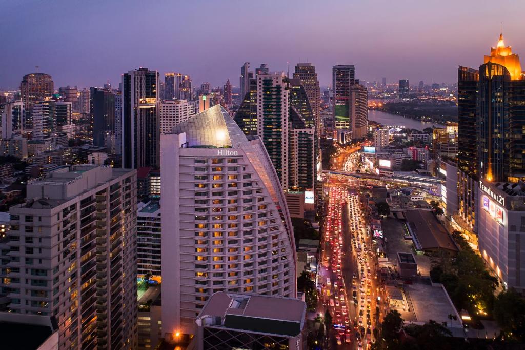 曼谷曼谷阿索克希尔顿酒店 - Hilton Bangkok Grande Asoke的城市天际线,夜晚有很多建筑