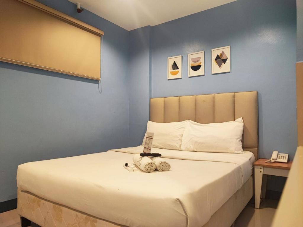 马尼拉Glory Hotel Cubao的一间卧室配有一张蓝色墙壁的床