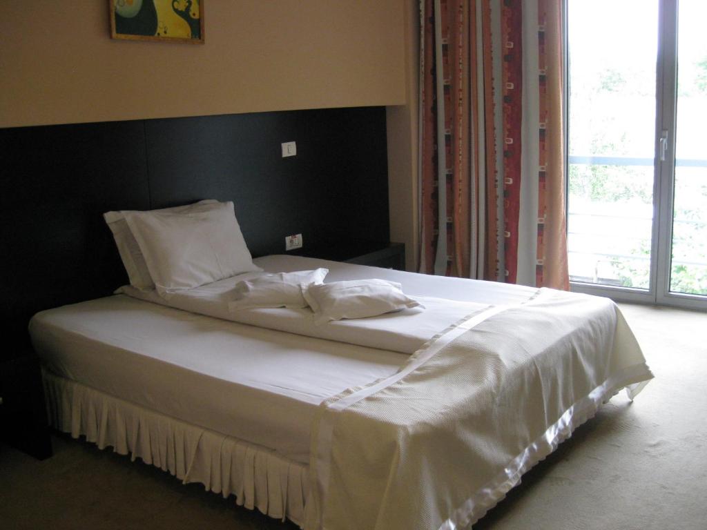 蒂米什瓦拉德派克酒店的卧室内的一张带白色床单和枕头的床