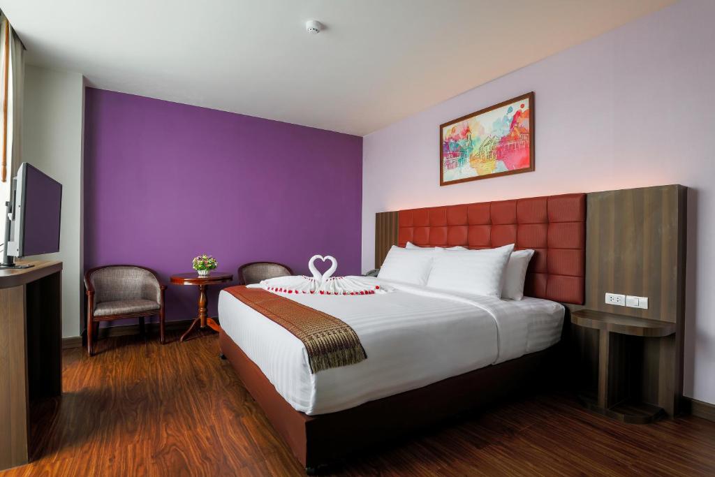 合艾Grandpink park hotel的酒店客房设有一张大床和紫色的墙壁。
