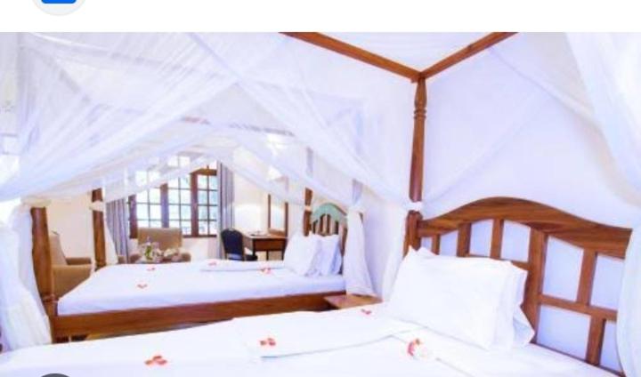 卡拉图MACHAGE TOURS AND SAFARIS HOTEL的一间卧室配有两张带白色床单的床