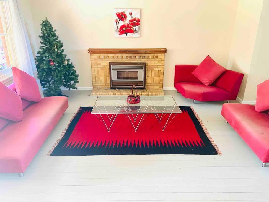 蚬壳港House At the Heart of Shellharbour的客厅设有红色的沙发和壁炉