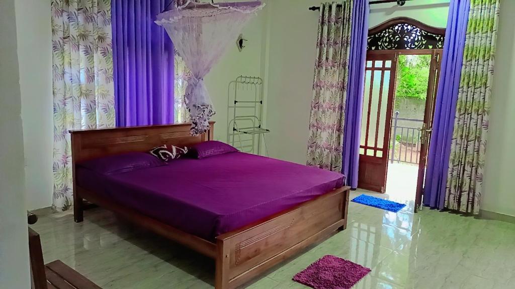 贝鲁沃勒Sunrise Relax Inn的窗户客房内的一张带紫色床单的床